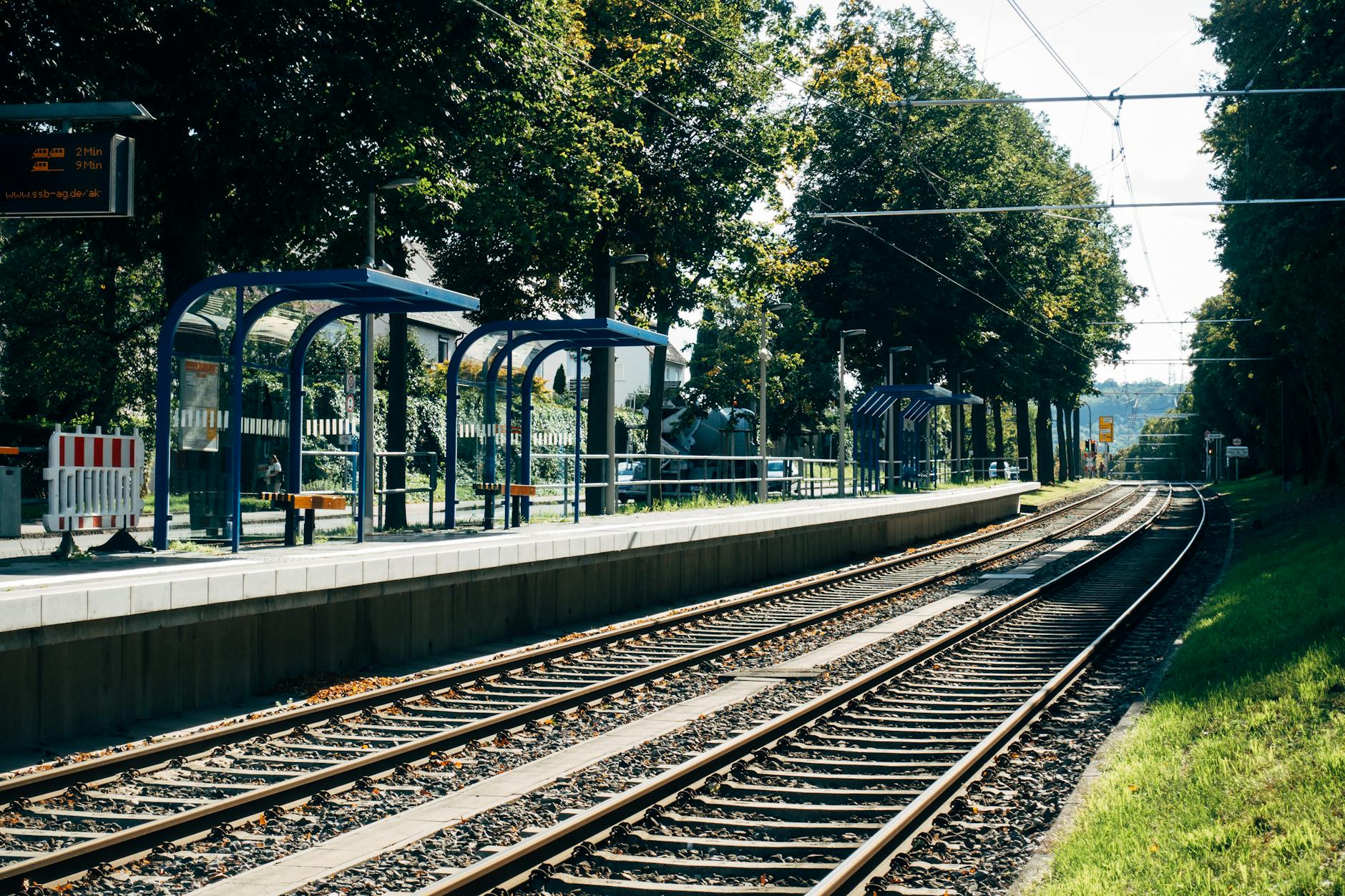 Scenic view of a train station platform and tracks in Stuttgart surrounded by greenery.