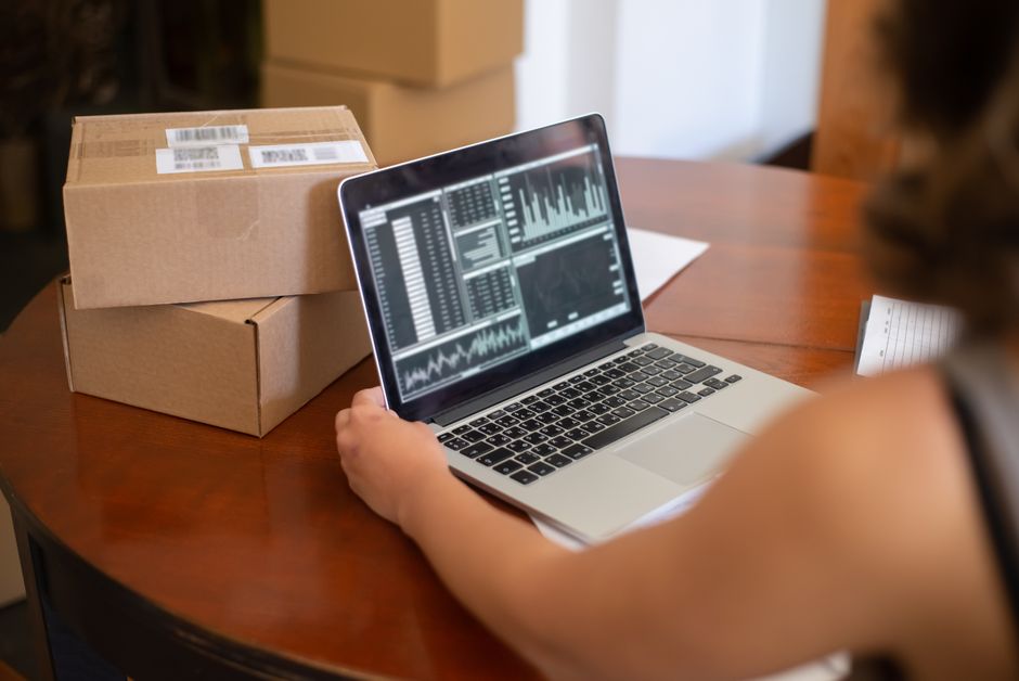 Small business owner managing online orders from a laptop with charts displayed