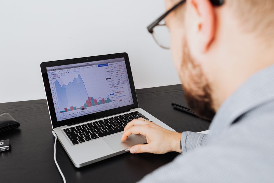 Business analyst working on a laptop evaluating competitor strategy and market analytics in modern office