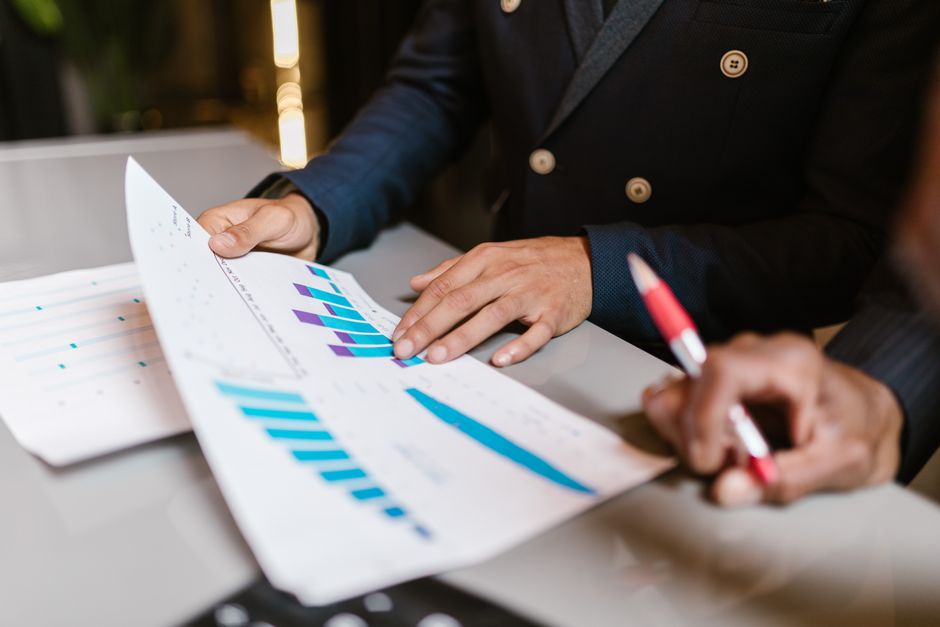 Close-up of professionals reviewing financial graphs and AI search analytics reports at a business meeting.