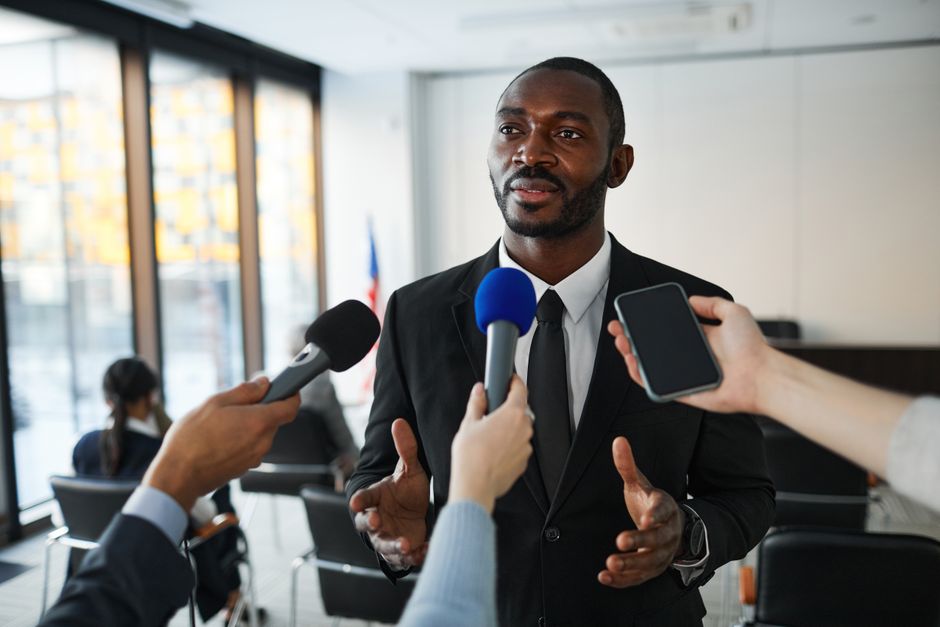 Confident businessman answering questions from the media during a press conference indoors