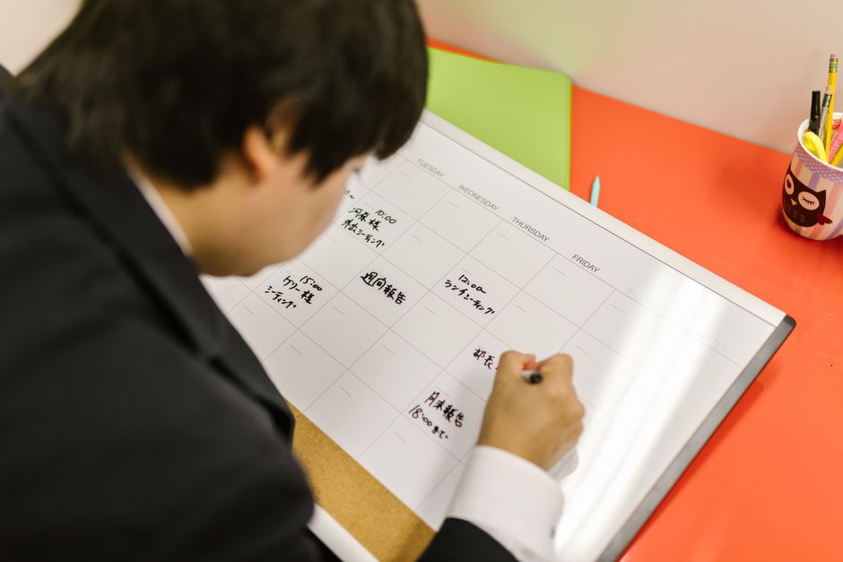 Businessperson writes in a planner on a desk, organizing weekly schedule professionally