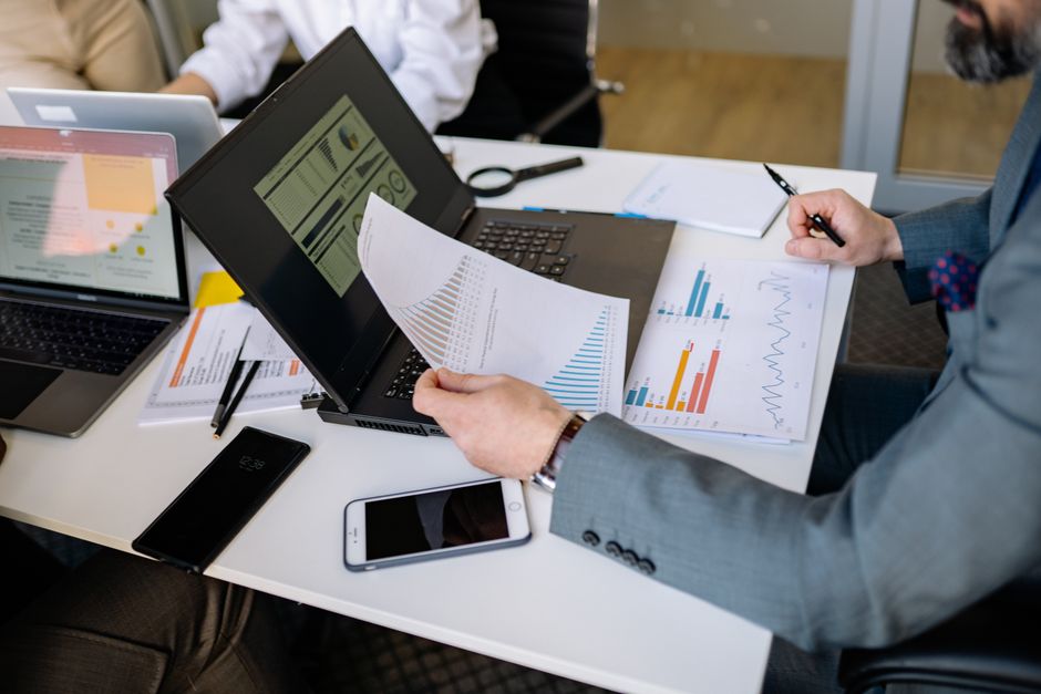 Professionals analyzing charts and graphs on laptops during a business meeting
