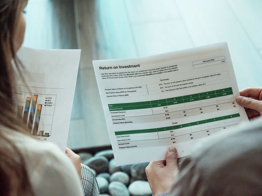 Close-up of two individuals analyzing financial documents related to return on investment