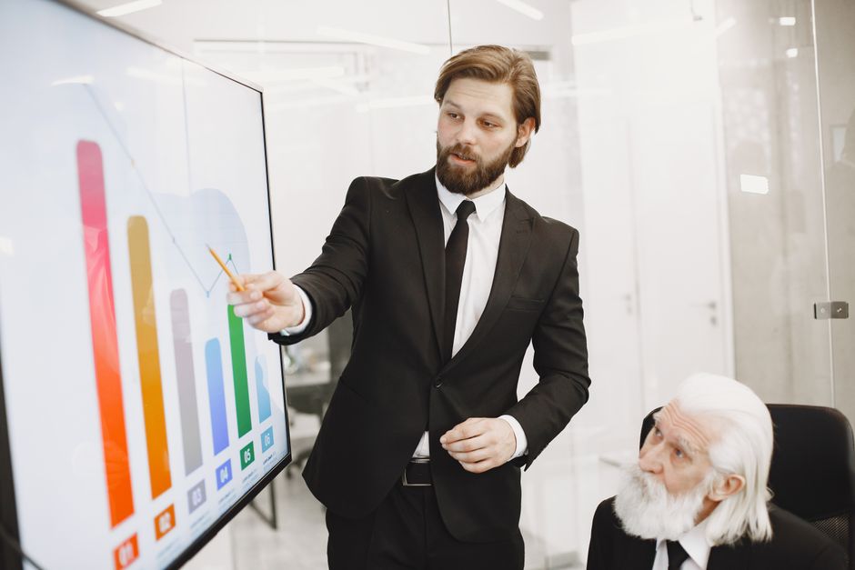 Two businessmen discussing data trends during a presentation in a modern office setting